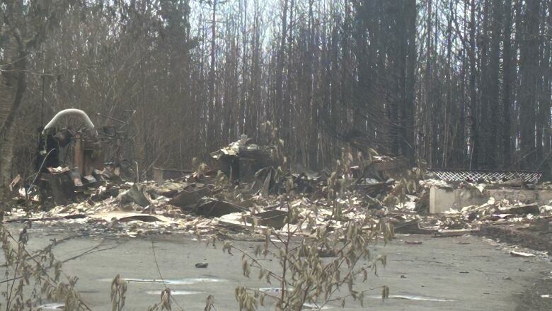 Charred remains of what was once a home, surrounded by burned trees.