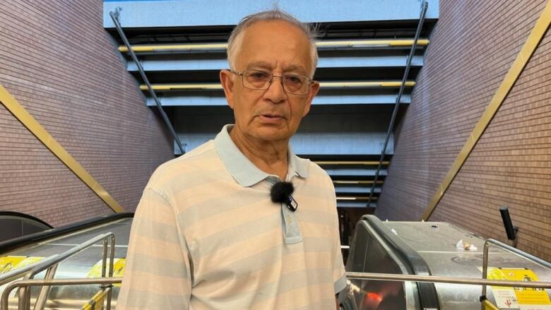 A man stands in front of an escalator.