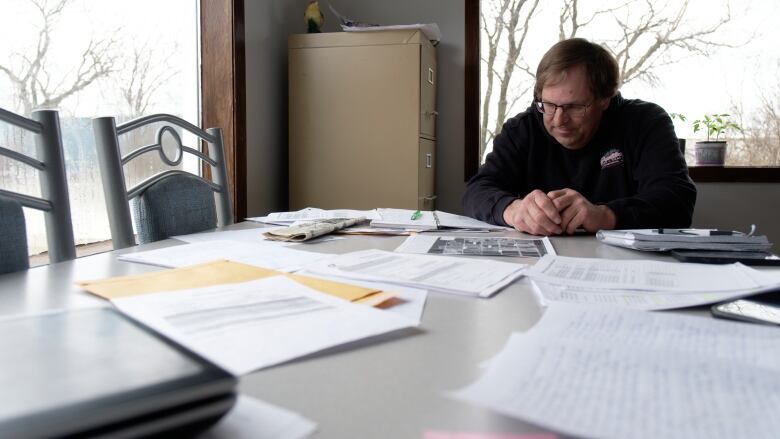 Mountney sits at table looking down toward various papers