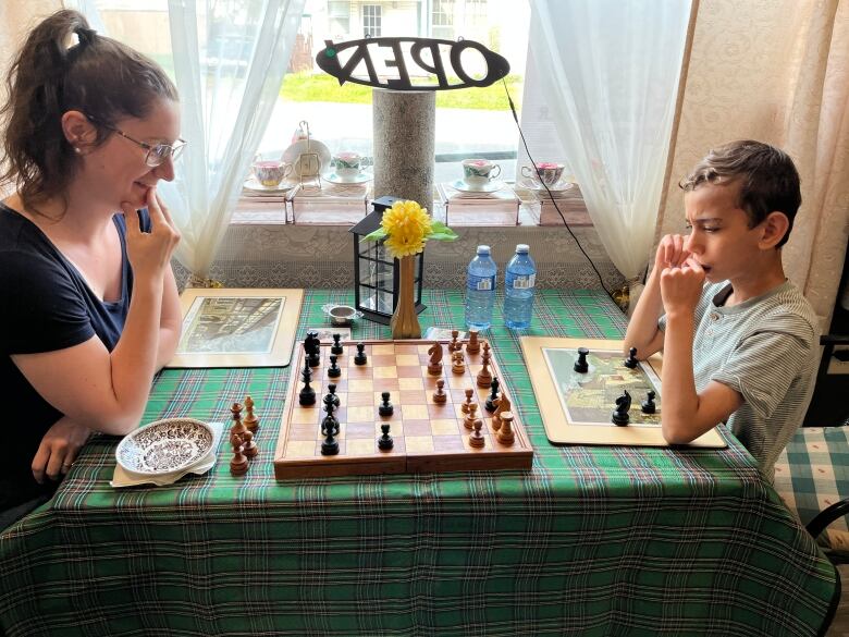 A woman play chess with a boy. 