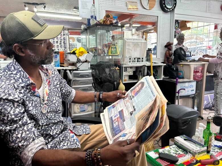 A man is sitting in a chair reading a newspaper.