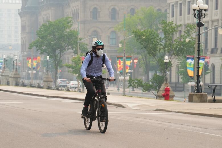 A cyclist rides his bike while wearing a mask due to the poor air quality in the aftermath of wildfires in Ontario and Quebec.