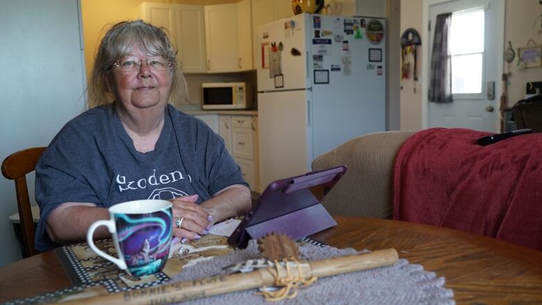 An older woman sitting in her home with a table on the table.