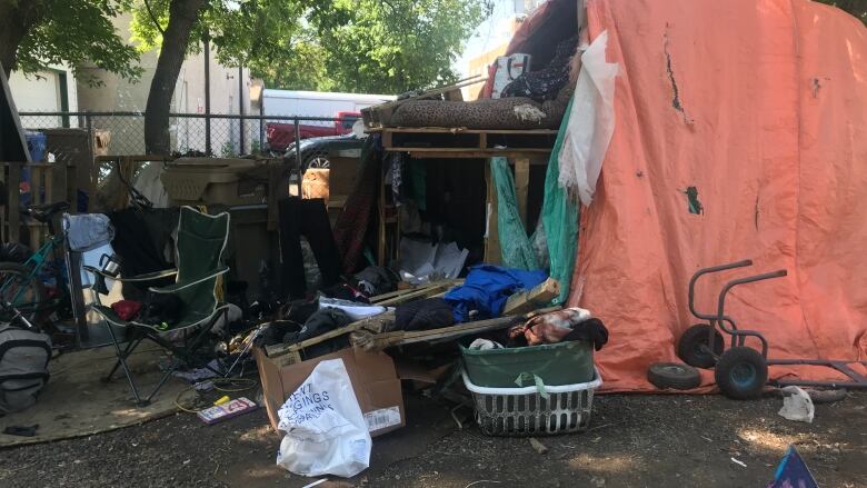 A tent that is constructed of several found items such as a chair, tarp, pallets, and other miscellaneous materials. 