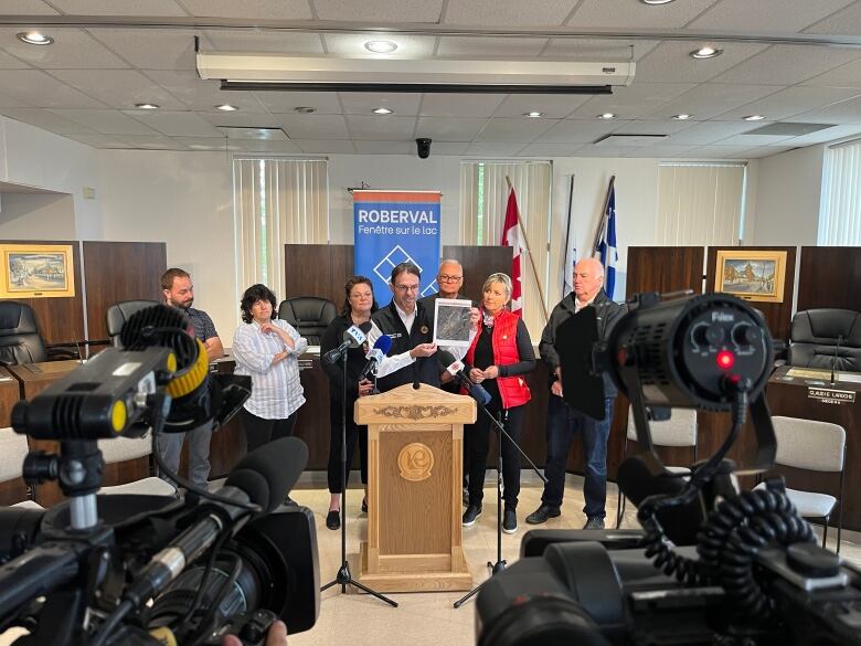 People stand in a room behind a podium.