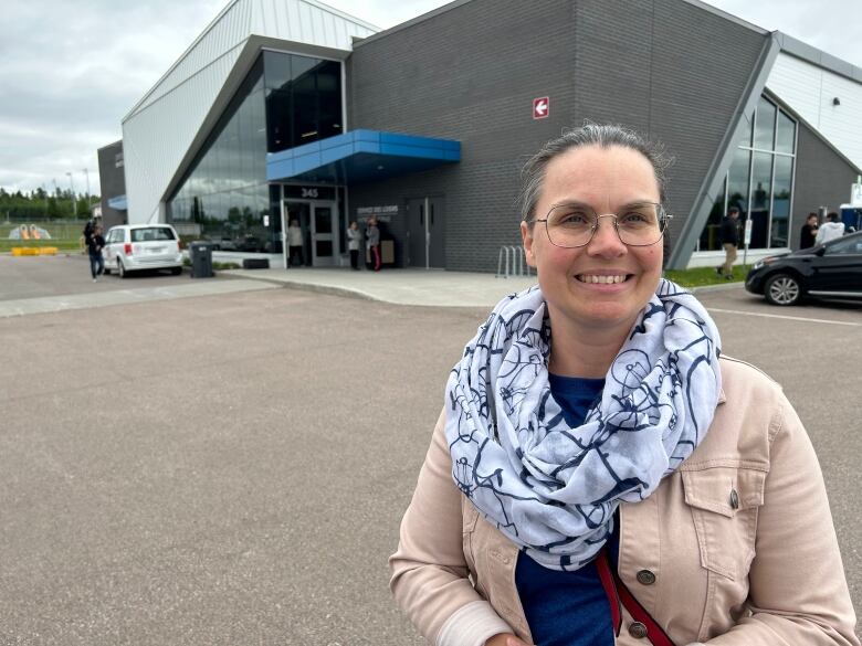 A woman smiling in a parking lot.