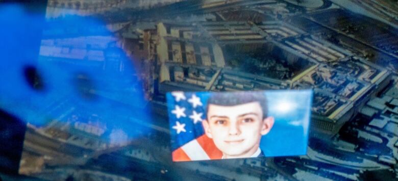 A posed photograph of a young person in a military uniform in front of an American flag is shown.