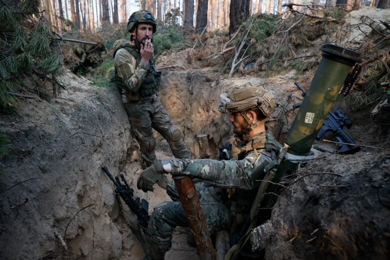 Two soldiers rest in a trench in Ukraine.