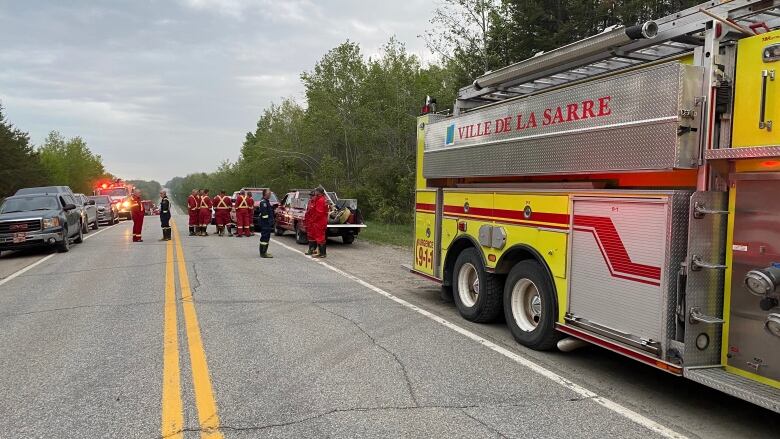 Fire truck in the foreground and firefighters in the background discussing. 