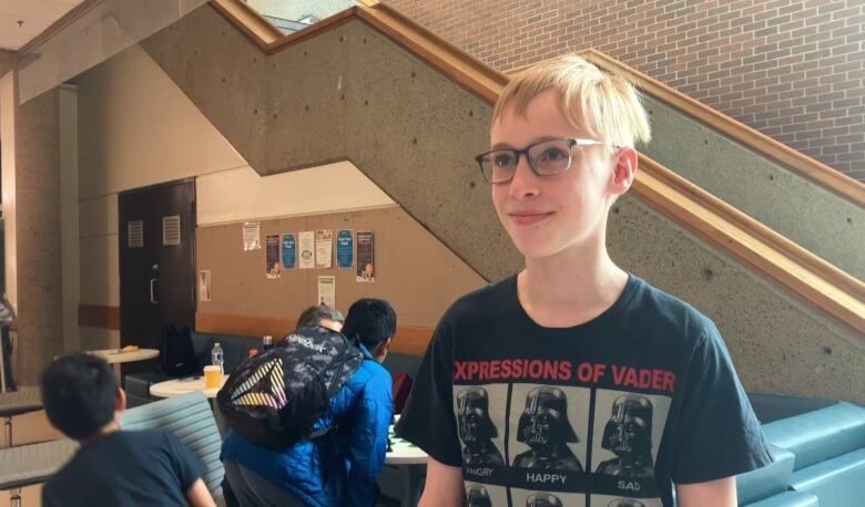 Louis stands in Saint Mary's University as people play chess behind him. 