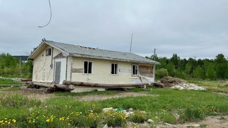 A home in deteriorating condition that is painted yellow. 