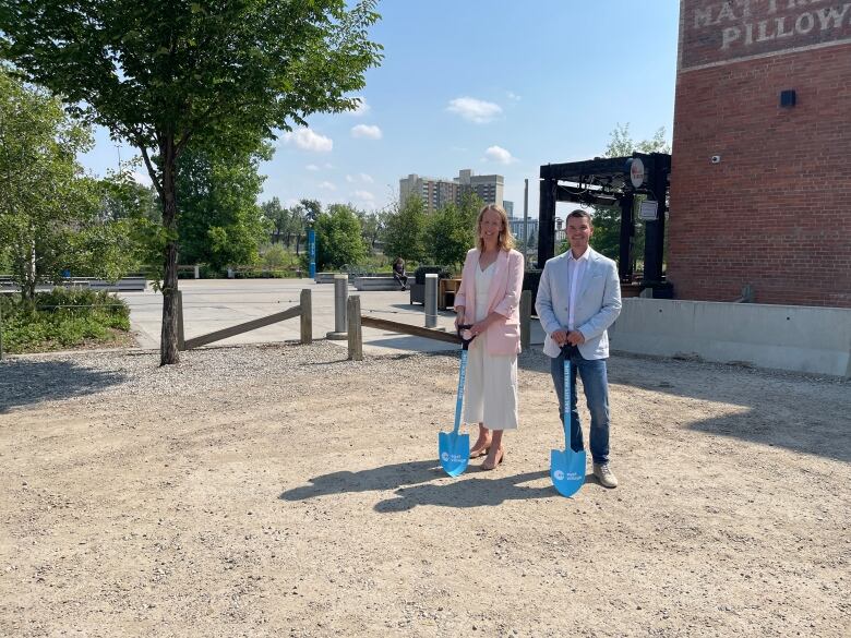 Two people holding shovels pose for a picture