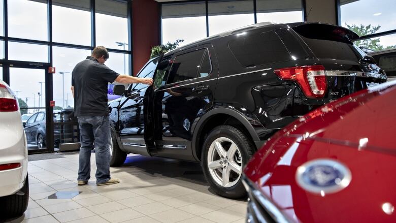 A man inspects an SUV at a Ford dealership.