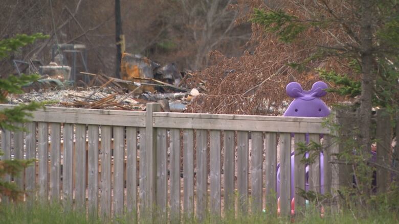 A wooden fence lines a property that was damaged by wildfire.