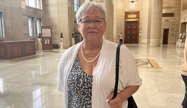 Audrey Hill in the lobby of the Supreme Court building with the Federal Court hearing room behind her.