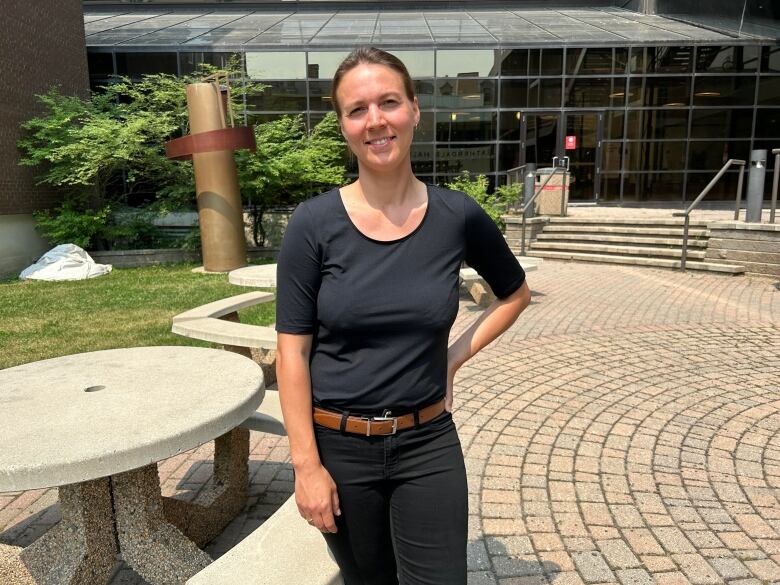 A woman in a black shirt and black pants is pictured in a courtyard.