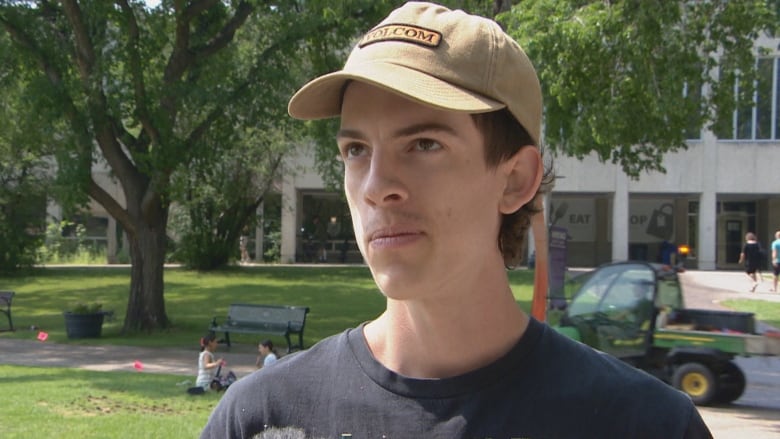 Adison Linberg is standing outside of the University of Saskatchewan with green grass and trees behind them.