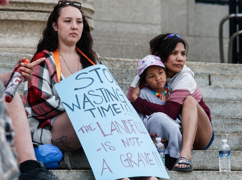 A woman hugs a child while sitting beside another woman.