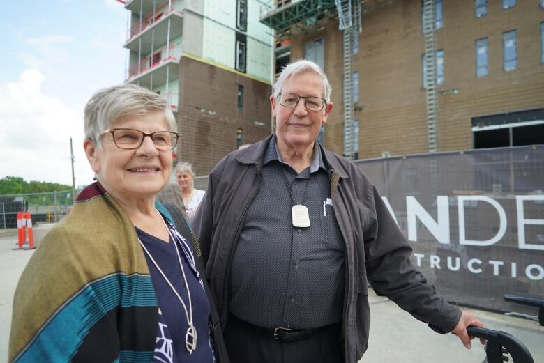 A senior couple stand in front of a building under construction.