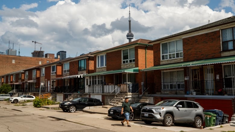 A row of Toronto houses, with the CN Tower peeking above the roofline in the background.