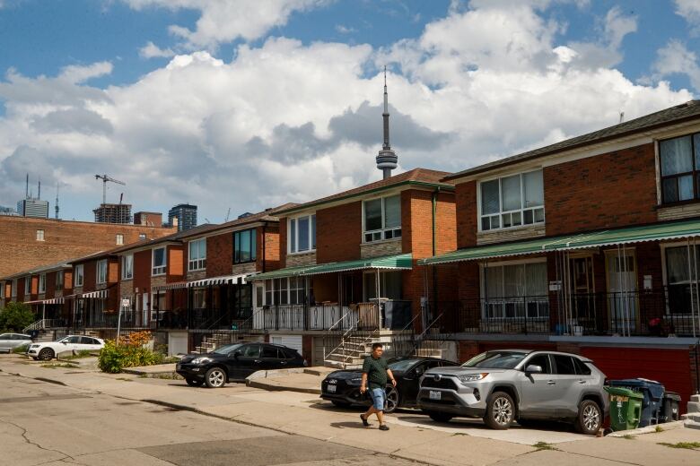 A row of Toronto houses, with the CN Tower peeking above the roofline in the background.