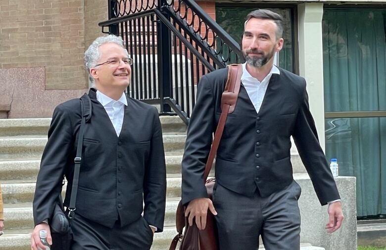 Two men walking down a set of stone steps.