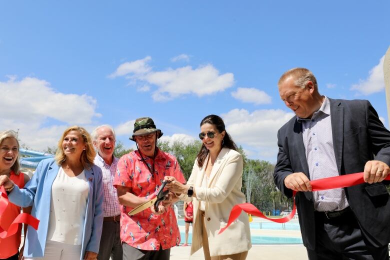 Five people take part in a ribbon cutting ceremony. 