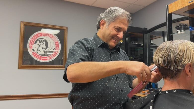 A man is cutting someone's hair. 