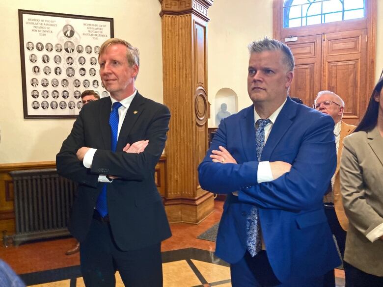 Two men standing side-by-side, arms crossed