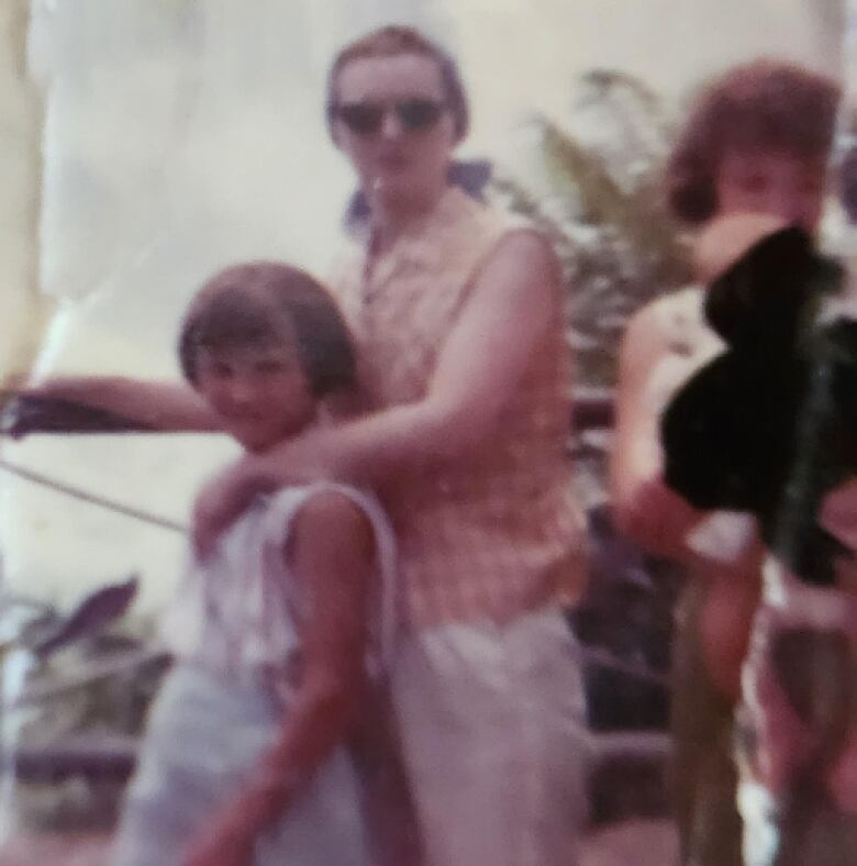 A blurry old colour photo of a woman and a child posing at Niagara Falls.