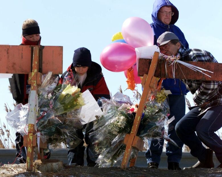 People look at flowers and notes at a makeshift memorial