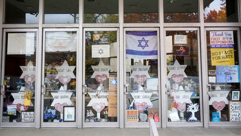 Several handmade signs as well as flags are shown in the window of a building.