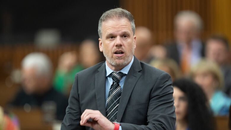 A man in a grey suit stands in the House of Commons.