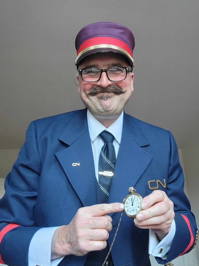 A man in a conductor suit holds a watch