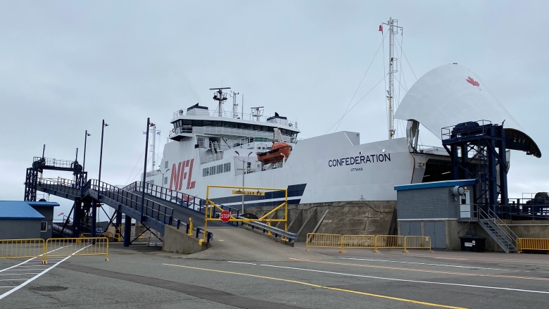 A large passenger and vehicle ferry is shown at dock with its nose cone open to accept vehicles. 