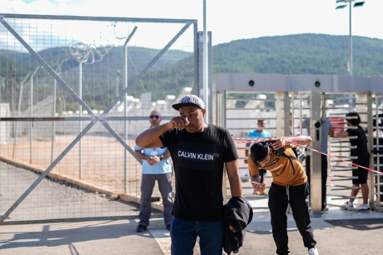 A man in the forefront cries as he walks away from a migrant camp.