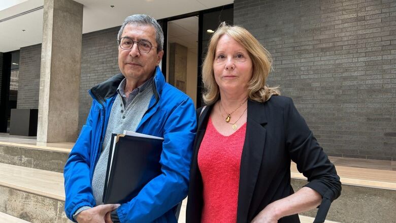 Two people stand in front of a building.