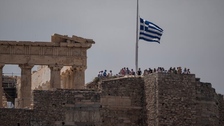 The Greek flag flies at half-mast next to Greece's ancient Parthenon temple. 