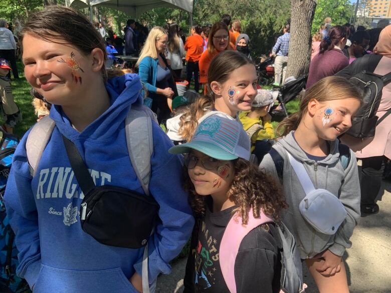 Four girls smile while showing the stylized dream catchers that are painted on their cheeks.