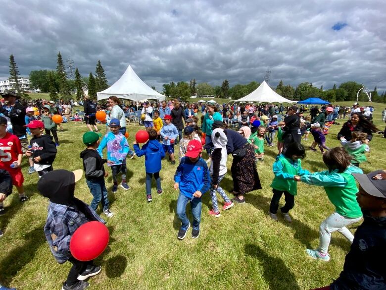 Kids dance and play with balloons in a park.