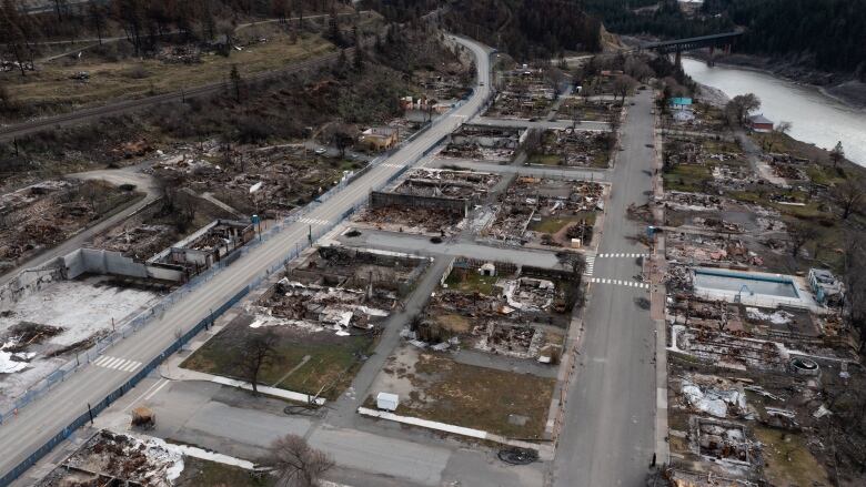 An aerial view of a village virtually destroyed by wildfires, with very few standing structures left.