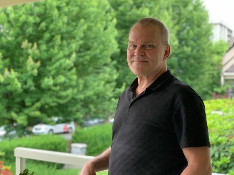 A white man in a black shirt smiles for a photograph.