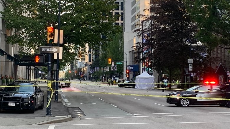 A view of Georgia Street at Burrard with police tape closing the intersections. Police vehicles are seen along with a white tent and two damaged vehicles.