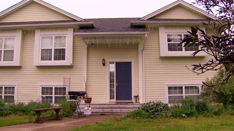 A yellow two-story home with a blue door is shown