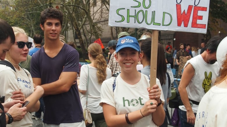 A young woman holds a sign that reads 