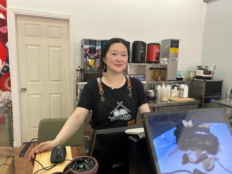 Woman in apron standing behind her businesses' counter