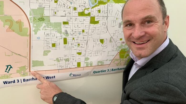 A city councillor smiles as he points to a map of his ward.