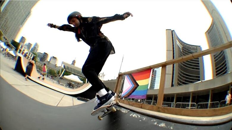 A skateboarder is shown doing a trick with the Pride Progress flag in the background.