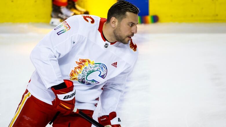 A male ice hockey player without a helmet skates with both hands on his stick before a game.