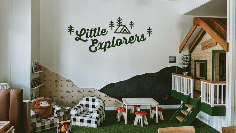 'Little Explorers' is written on the wall above a children's play area that had little tables, a playhouse and stuffed animals.